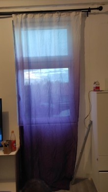 Blick durch einen Vorhang auf ein vollständig ausgetauschtes Fenster.